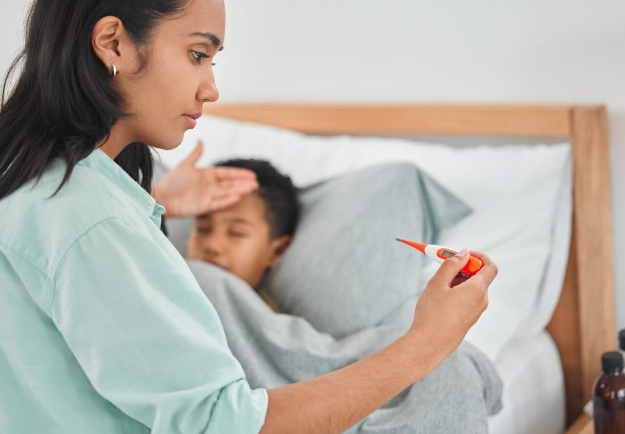 Un parent prend délicatement la température rectale de son bébé avec un thermomètre numérique.